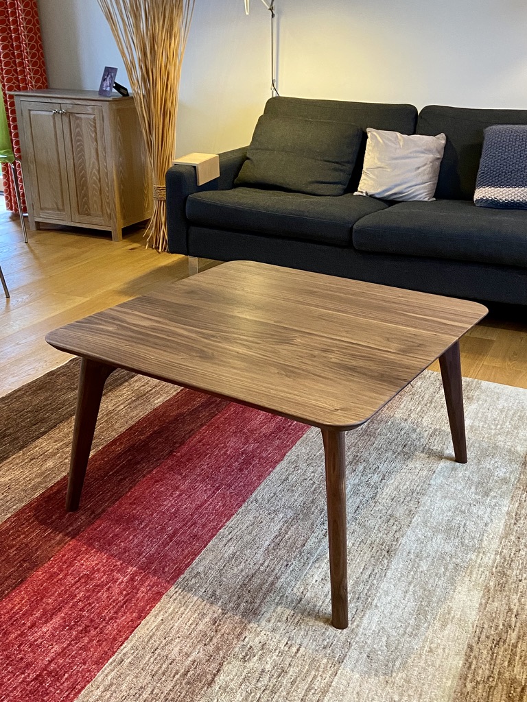 Bespoke walnut coffee table with rounded corners and tapered legs, in a living room setting