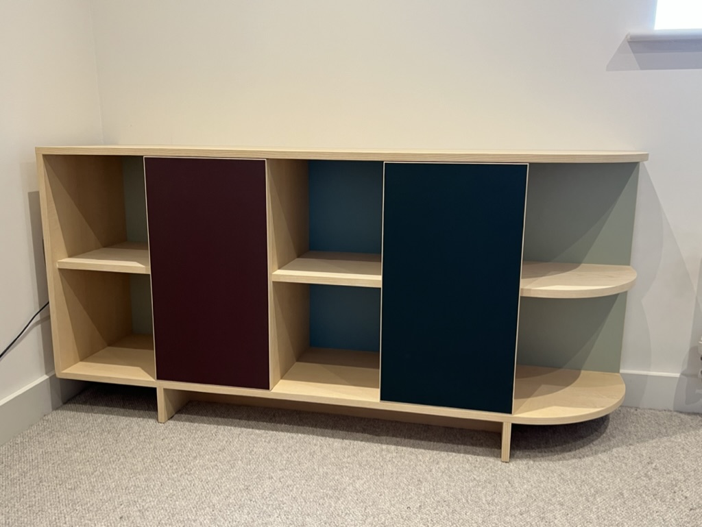 Bespoke oak shelving unit with coloured sliding doors in teal and burgundy, custom-made by Mark Eden Design