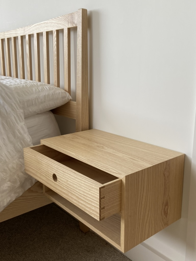 Bespoke ash bed with slatted headboard and matching wall-mounted bedside table with dovetailed drawer