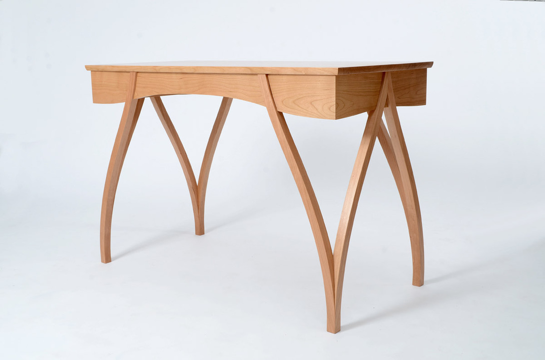 Bespoke cherry writing desk with arched crossed legs, three-quarter view, handmade in the Lake District